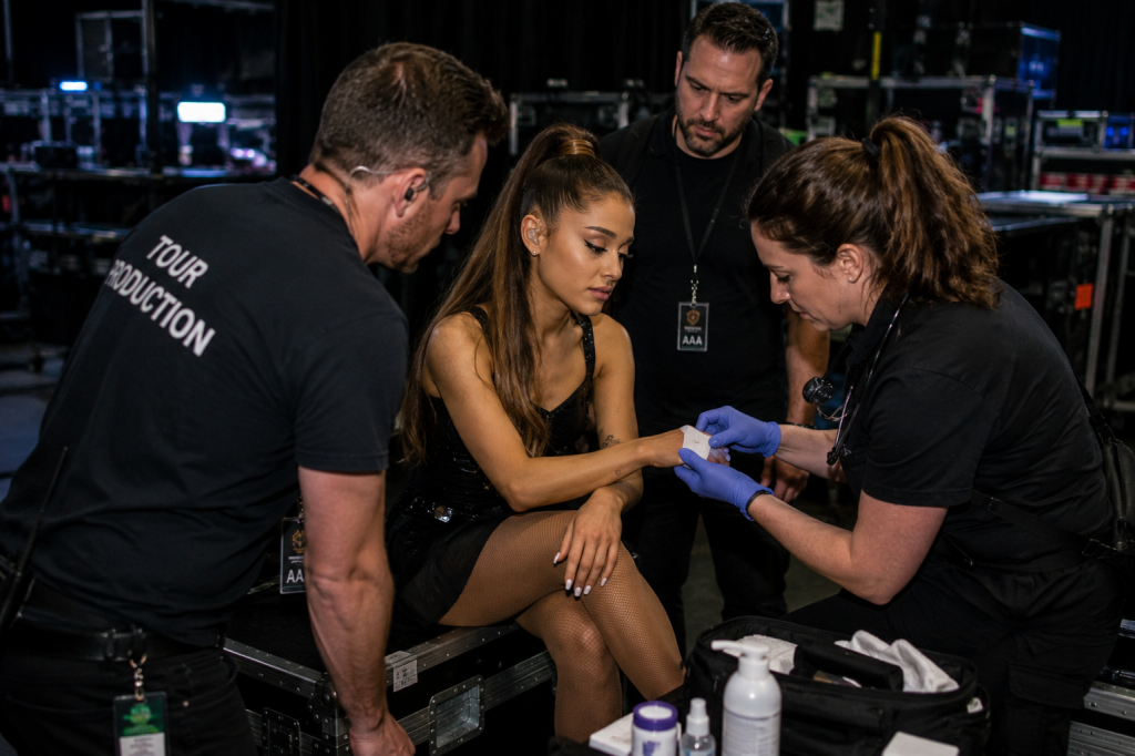 Medical and production staff assisting performer backstage during concert tour preparation
