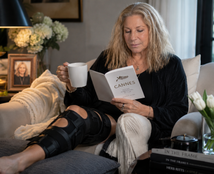 Older female celebrity resting at home with a knee brace after canceling a major film festival appearance