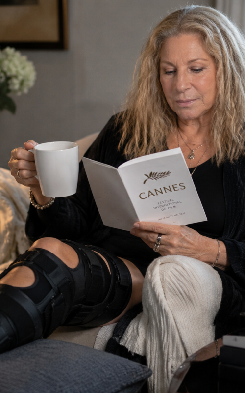 Older female celebrity resting at home with a knee brace after canceling a major film festival appearance