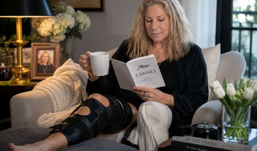 Older female celebrity resting at home with a knee brace after canceling a major film festival appearance