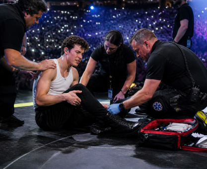 Singer receiving medical attention on stage during live performance