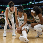 A female professional basketball player clutching her knee in pain on the hardwood court during a game