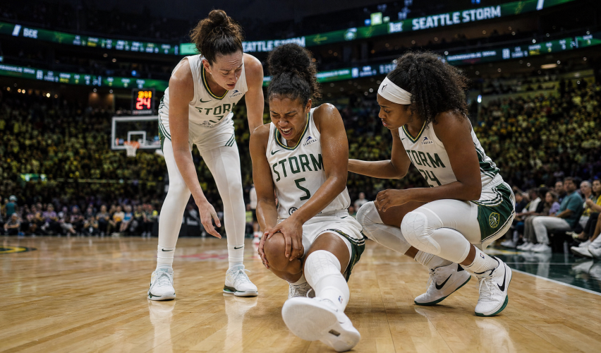A female professional basketball player clutching her knee in pain on the hardwood court during a game