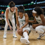 A female professional basketball player clutching her knee in pain on the hardwood court during a game