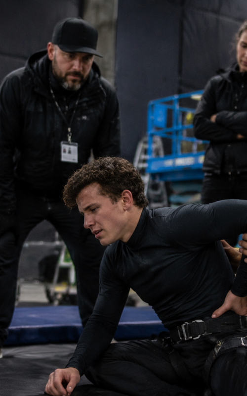 Actor performing action stunt rehearsal with safety crew after possible back injury concern